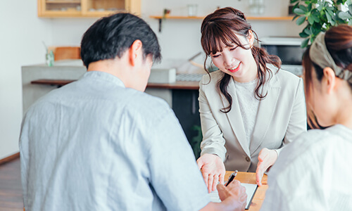 ビジネススーツを着た女性がお客様を相手にヒアリングしている様子のイメージ画像