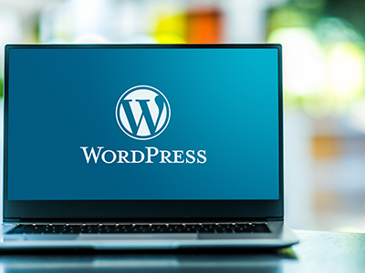 ノートパソコンにWordPressのロゴとテキストが映し出されているイメージ画像