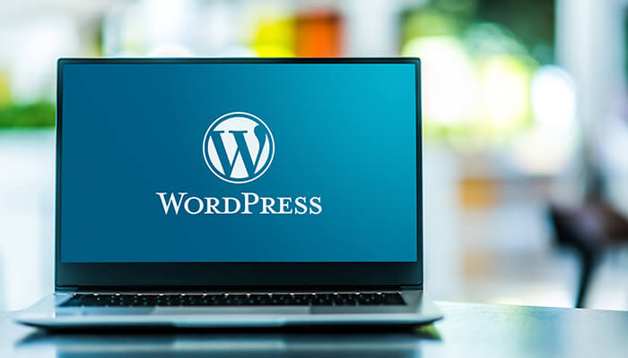 ノートパソコンにWordPressのロゴとテキストが映し出されているイメージ画像